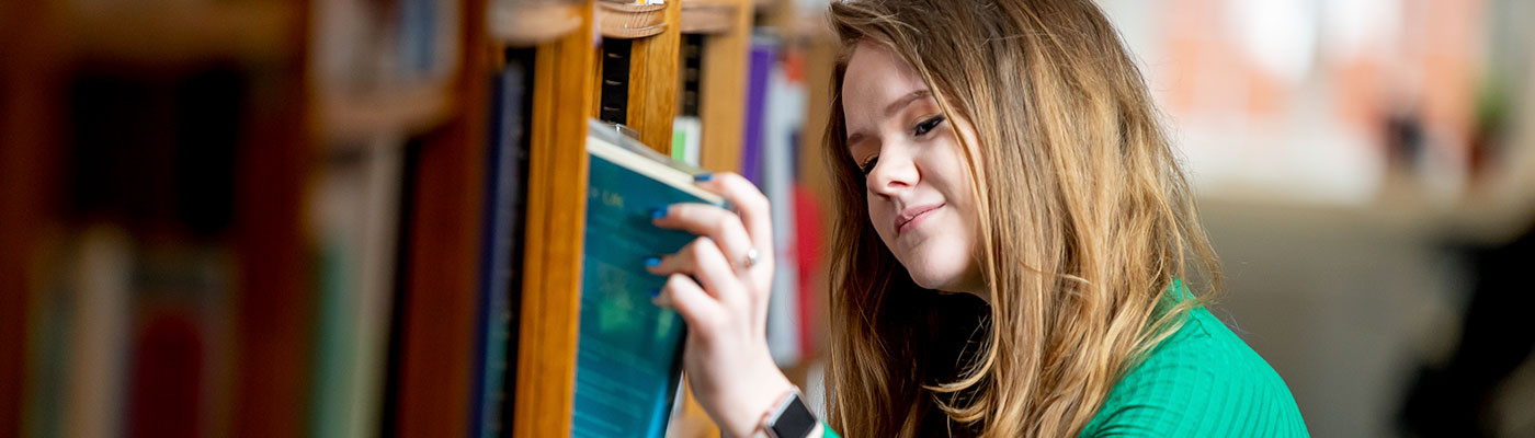 Student choosing a book in the library