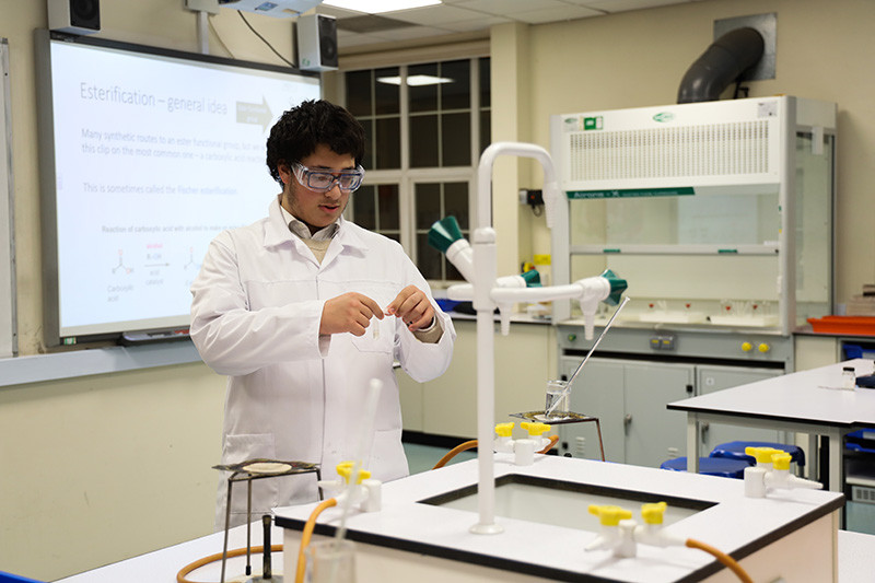 George makes sure the two halves of his shortened plastic pipette (the reaction vessel) fit together before collecting his reagents from the fume hood in the background.